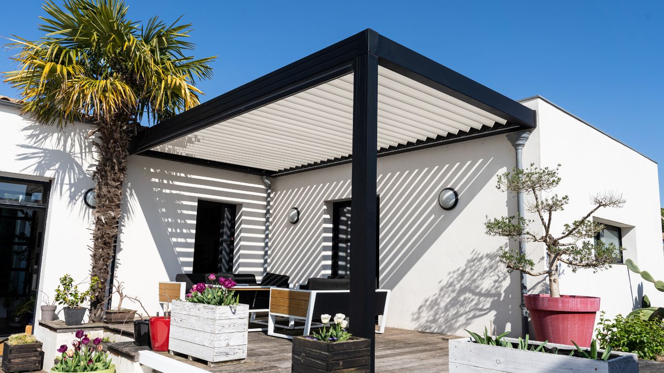 Pergola moderne en métal avec lames orientables, installée sur une terrasse avec mobilier de jardin, conçue par Ferronnerie Ferafer.