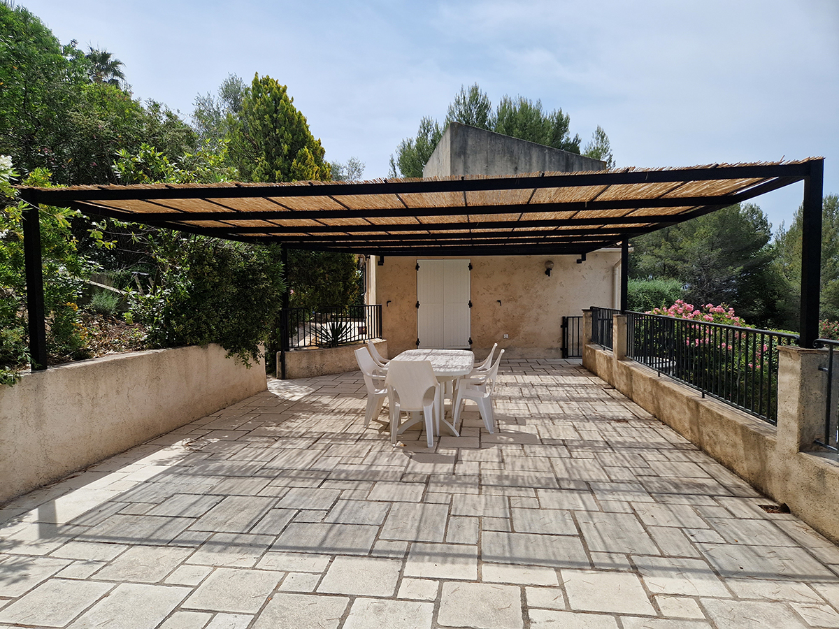 Pergola moderne en fer forgé avec toile rétractable, installée sur une terrasse en pierre avec mobilier de jardin, conçue par Ferronnerie Ferafer.