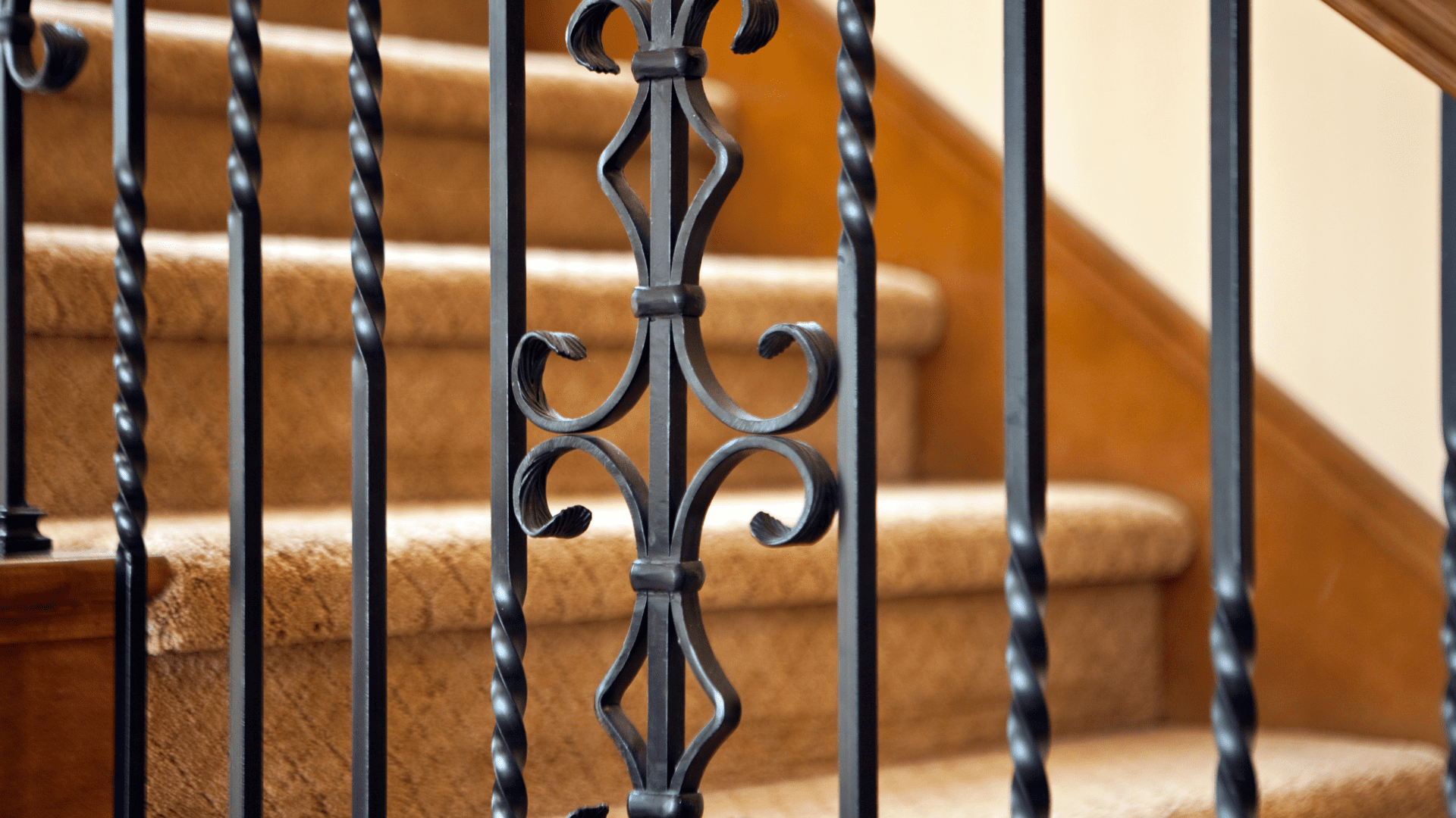 Garde-corps en fer forgé avec motifs torsadés et volutes, installé le long d’un escalier en bois, conçu par Ferronnerie Ferafer.